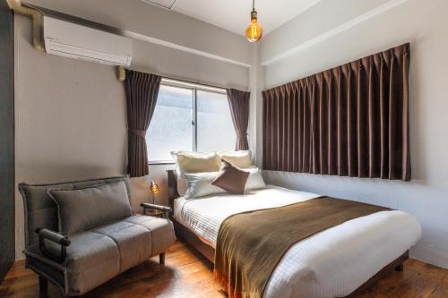 a bedroom with a bed and a chair and a window at Residential Hotel Naha Miebashi in Tomari