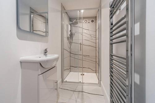 a white bathroom with a sink and a shower at Modern 3BHK near Edinburgh zoo in Edinburgh