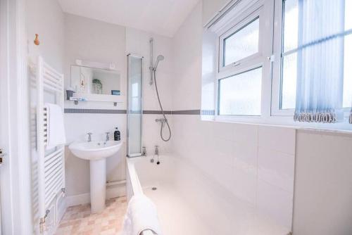 a white bathroom with a shower and a sink at 1 Albert Terrace - Southwold in Reydon