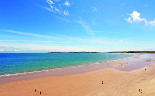 a group of people on a beach with the ocean at Coral Shepherds Hut in Penally