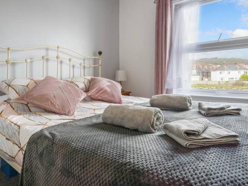 a bed with towels and pillows on it with a window at River View Walk - Fab 3B House in Aberystwyth