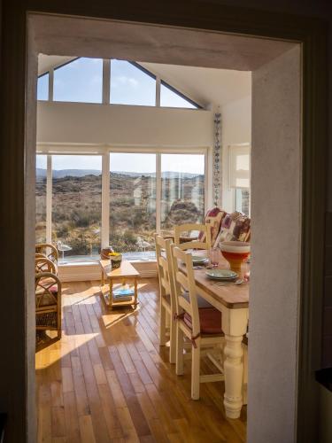 a dining room with a table and a large window at 14 Leitirshask, Ballyconneely in Ballyconneely