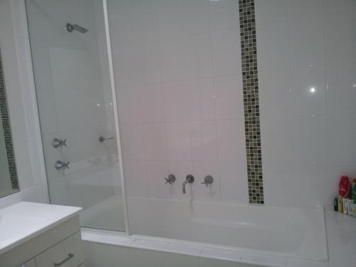 a white bathroom with a shower with a glass door at Entire 2BR sunny house @Franklin, Canberra in Canberra