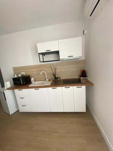 uma cozinha com armários brancos e um lavatório em Apartament Grand Hill 1 em Oradea