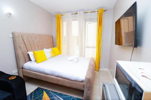 Schlafzimmer mit einem Bett und einem Fenster mit gelben Vorhängen in der Unterkunft Jay Cosy Homes in Kiambaa