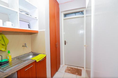 een kleine keuken met een wastafel en een deur bij Jay Cosy Homes in Kiambaa