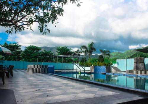 a resort swimming pool with a view of the mountains at Wayfare SP Resort in Panvel