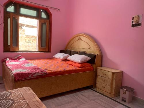 Cama en habitación con pared de color rosa en MOON HAVELI, en Bikaner