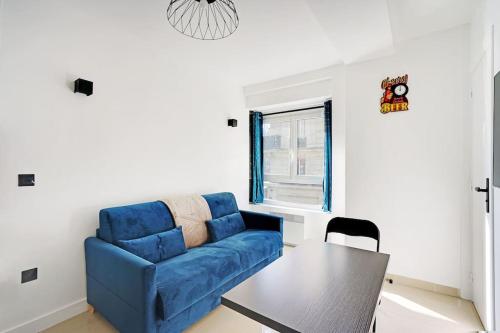 un salon avec un canapé bleu et une table dans l'établissement Appartement - Paris, à Paris