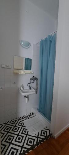 a bathroom with a sink and a blue shower curtain at Central Room Hostel in Balatonszárszó