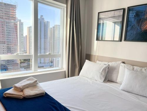 um quarto com uma cama branca e uma grande janela em Blend SmartStyle by Marzani Host em Goiânia