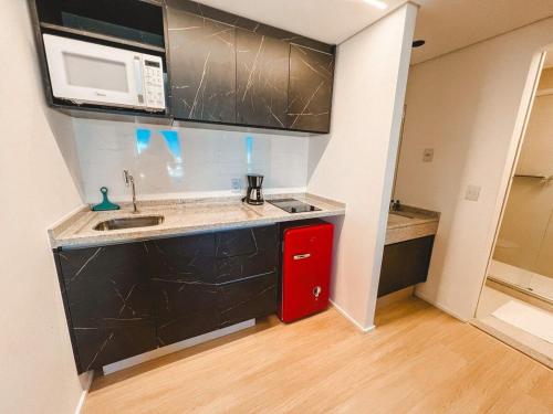 a small kitchen with a sink and a microwave at Blend SmartStyle by Marzani Host in Goiânia