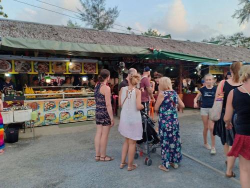 a group of people standing in front of a market at Freedom​ Hostel​ in Khao Lak