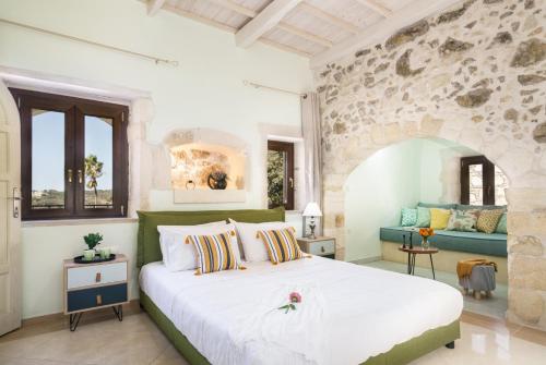 a bedroom with a large bed and a stone wall at Butterfly, a historical villa with pool & hot tub! in Arménoi