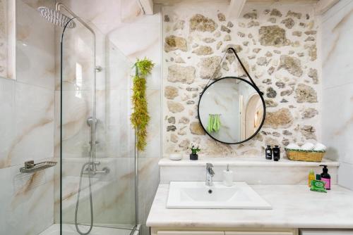 a bathroom with a shower and a sink and a mirror at Butterfly, a historical villa with pool & hot tub! in Arménoi