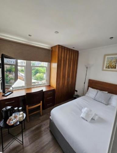 Schlafzimmer mit einem weißen Bett, einem Schreibtisch und einem Fenster in der Unterkunft Cosy Double Room City Centre in Edinburgh