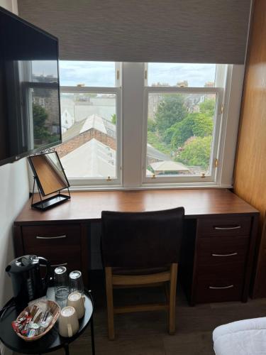 einen Schreibtisch mit Stuhl in einem Zimmer mit Fenster in der Unterkunft Cosy Double Room City Centre in Edinburgh