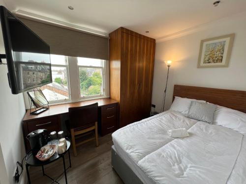 Schlafzimmer mit einem Bett, einem Schreibtisch und einem TV in der Unterkunft Cosy Double Room City Centre in Edinburgh