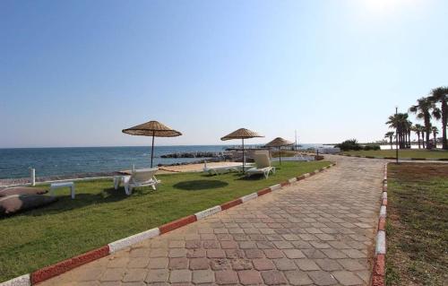 un camino de ladrillo con sillas y sombrillas en la playa en Didim Parlamenter Villa Denizli Havuzlu, en Didim