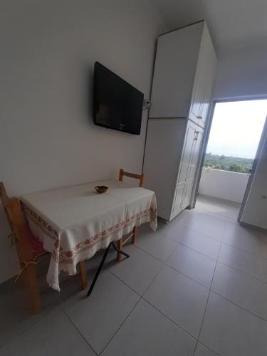 een witte kamer met een tafel en een koelkast bij Borsh Amantius Apartments in Himare