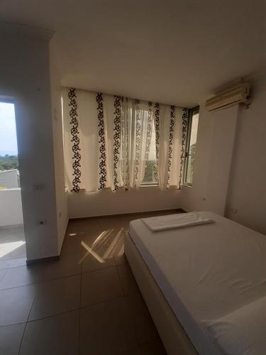 1 dormitorio con 1 cama y una ventana con cortinas en Borsh Amantius Apartments en Himare