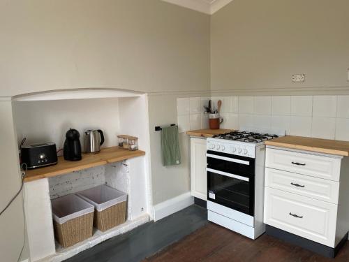 a kitchen with a stove and white cabinets at Bullock and Company Cottage in Toodyay