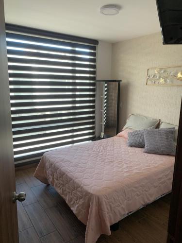 a bedroom with a bed and a large window at Hermosa casa cerca de Aeropuerto in Quito