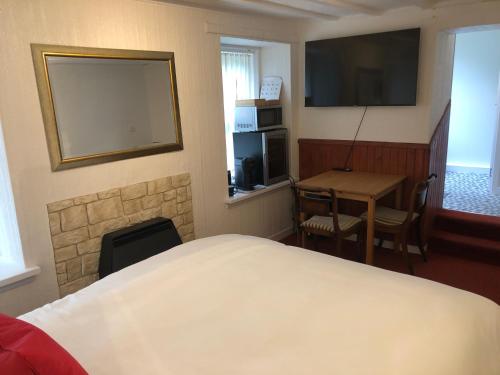 1 dormitorio con cama, mesa y TV en Ardvane Bed & Breakfast, en Pitlochry