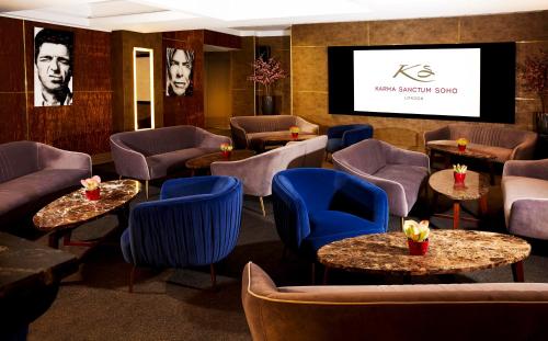 a restaurant with blue chairs and tables and a tv at Karma Sanctum Soho Hotel in London
