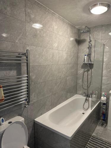 a bathroom with a tub and a toilet and a shower at Dartford Luxurious House with Parking - Netflix - Wi-Fi in Kent