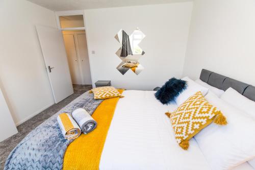 Un dormitorio con una cama blanca con almohadas amarillas y azules en Dartford Luxurious House with Parking - Netflix - Wi-Fi, en Kent