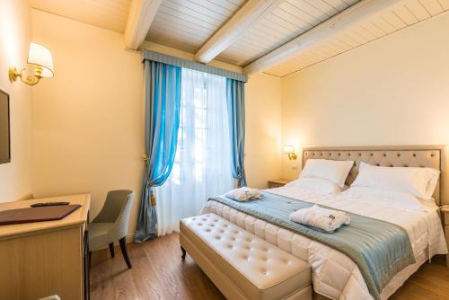 a bedroom with a bed with a desk and a window at Relais Paradiso Resort & Spa in Gualdo Cattaneo