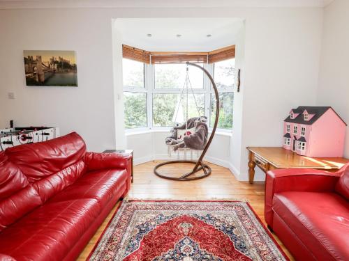 a living room with a red leather couch and a swing at Trem Y Don in Dolgarrog