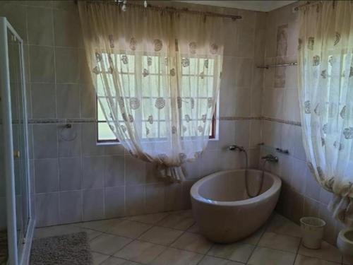 a bathroom with a tub and a shower with curtains at The Sanctuary - Self Catering Accommodation in Mtubatuba