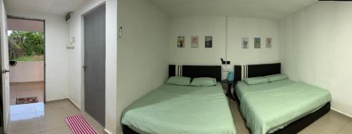 two beds in a room with a room with a window at Sungai endau bilik homestay in Kuala Rompin