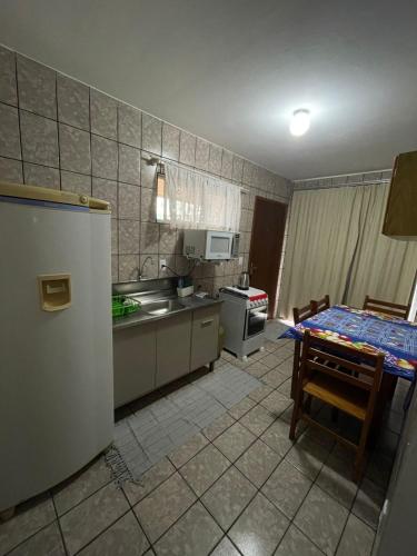 eine Küche mit einem Kühlschrank und einem Tisch darin in der Unterkunft APARTAMENTO PARA 4 ADULTOS EM BALNEARIO CAMBORIU in Balneário Camboriú