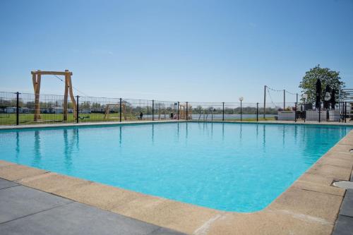 une grande piscine bleue avec une aire de jeux vide dans l'établissement De Lithse Ham, à Lith