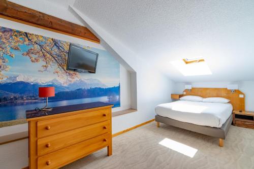 1 dormitorio con 1 cama y TV en la pared en Hôtel Beau Site, en Malbuisson