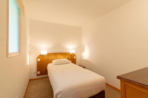 a small bedroom with a white bed and a window at Hôtel Beau Site in Malbuisson