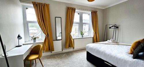 een slaapkamer met een bed, een bureau en ramen bij Habershon by Switchback Stays in Cardiff