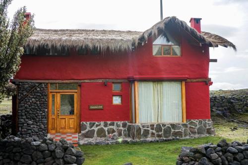 a red house with a thatched roof at Hotel Tambopaxi in Machachi
