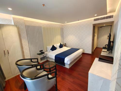 een hotelkamer met een bed en een tafel met een kruk bij The Emerald Hotel & Siya Milan Banquets in Muzaffarpur