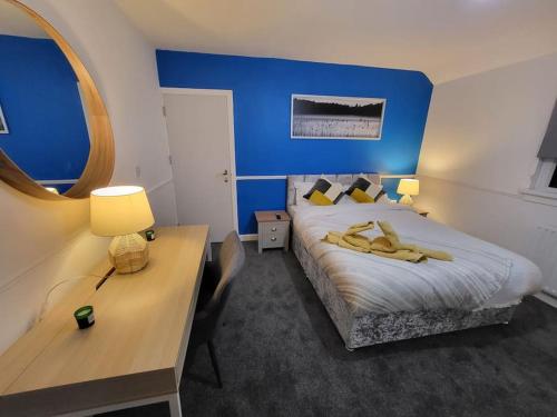 a room with a bed with a desk and a blue wall at 3 Bed House, free parking. Great for work crews - Stay Sleep Rest in Nottingham