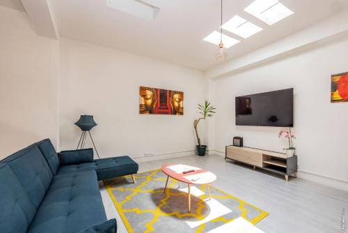 sala de estar con sofá azul y TV en LOFT COSY - HYPERCENTRE - SAUNA - 200m2 - WIFI en Graulhet