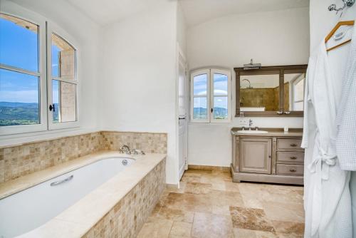 La salle de bains est pourvue d'une baignoire, d'un lavabo et de fenêtres. dans l'établissement Beautiful Provençal Mas in the Golfe de Saint-Tropez, à Cogolin