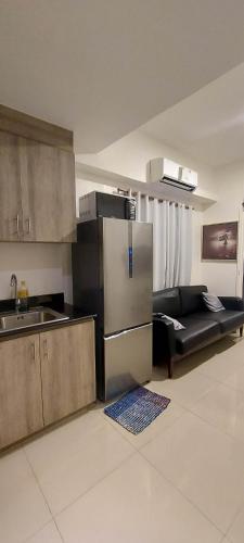 uma cozinha com um frigorífico de aço inoxidável e um sofá em 2 Bedroom with Balcony/ Family Room em Manila