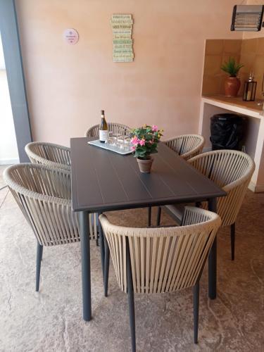 a table with chairs and a bottle of wine and flowers at Cas Padrins de ses Tanques in Ariany