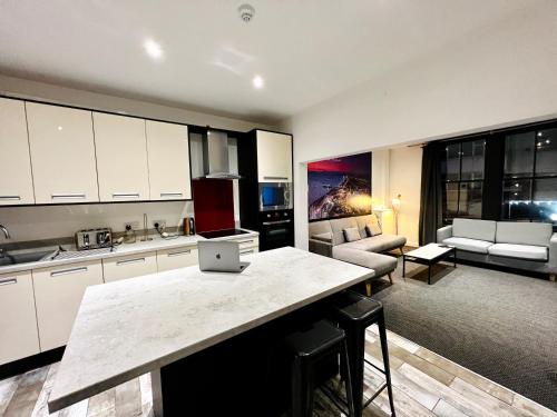 a kitchen and living room with a laptop on a counter at The Pier Suite Serviced Apartment Blackpool in Blackpool