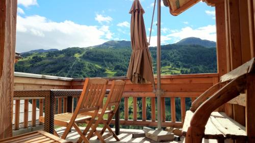 d'une terrasse avec un parasol et une chaise sur le balcon. dans l'établissement Chalet with Ski Slope Views, Jacuzzi & Cinema Room, à Vars