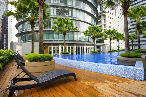a pool in a building with palm trees and a bench at Vortex Klcc Penthouse Twins Tower View in Kuala Lumpur